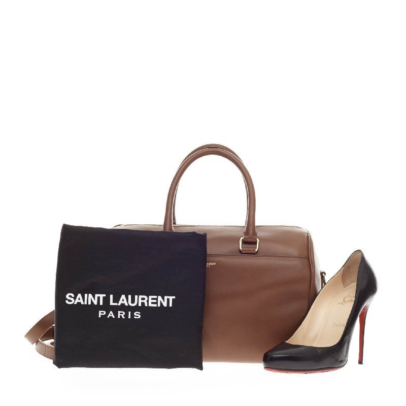 This authentic Saint Laurent Classic Duffle Leather 12 is a sleek, modern and an elegant duffle bag to travel in style with. Crafted in traditional brown leather and gold-tone hardware accents, this alluring bag can be carried as a convenient