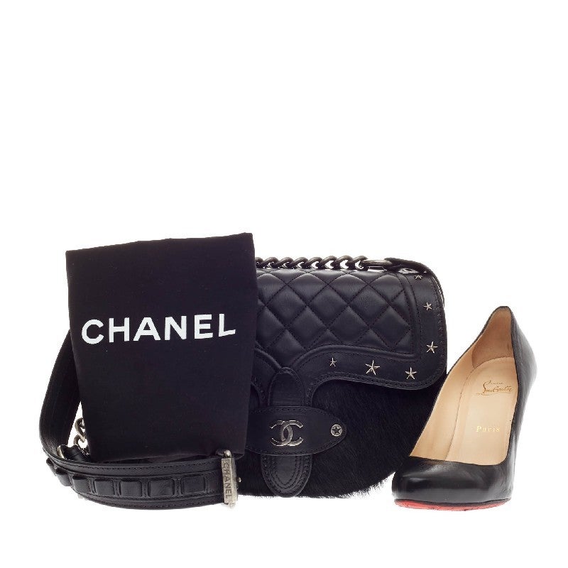 This authentic limited edition Chanel Dallas Studded Saddle Bag Quilted Calfskin and Pony Hair showcased in Chanel's Metiers d'Art 2014 collection mixes the brand's avant-garde style with a flair of Texas inspiration. Crafted from quilted black