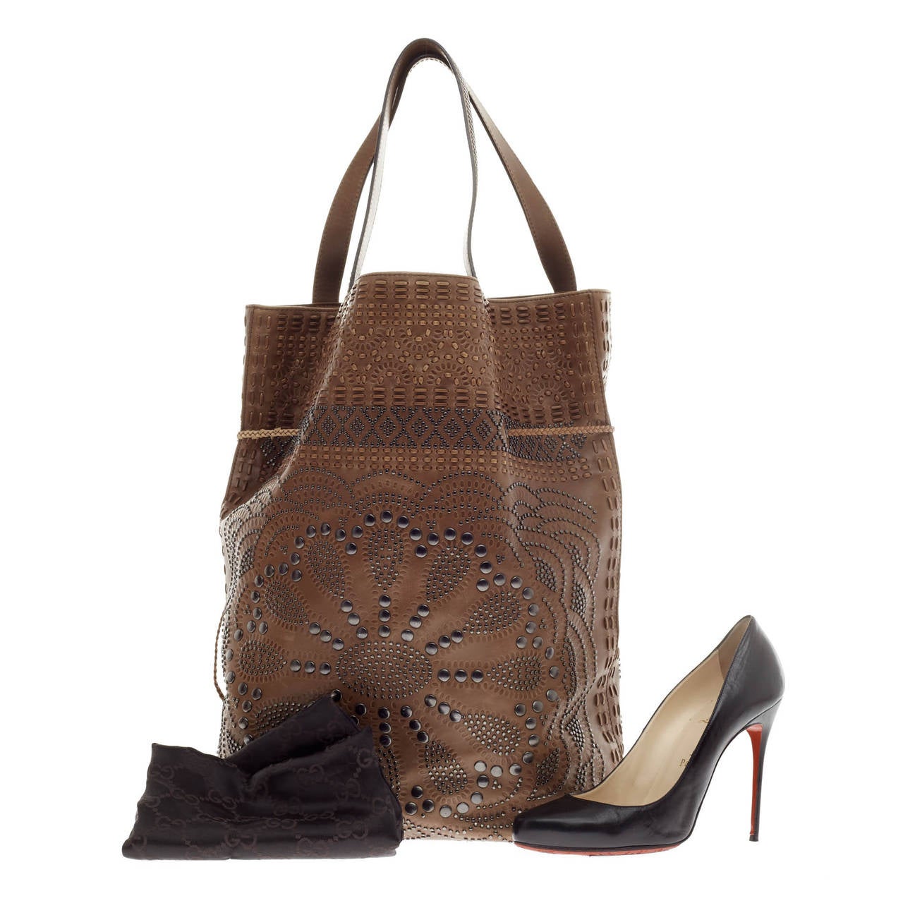 This authentic Gucci Studded Drawstring Hobo Leather showcases a vintage western-inspired style with a feminine twist. Crafted from supple brown leather, this drawstring hobo features antique floral stud detailing, stitched accents and a cinched