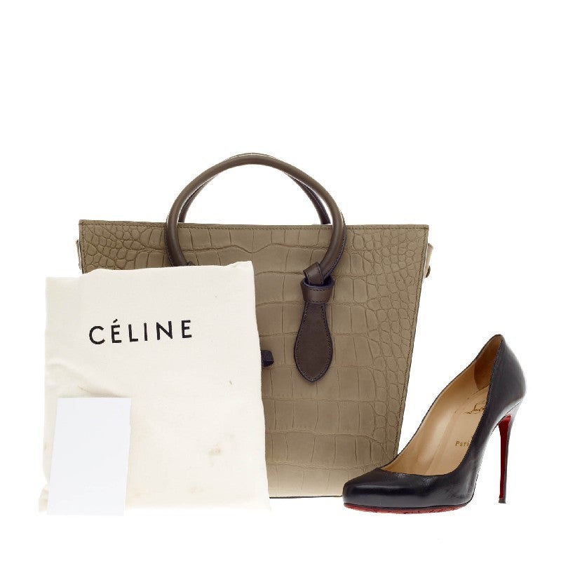 This authentic Celine Tie Tote Stamped Nubuck Mini is an absolute must-have for serious fashionistas. Crafted from ash gray nubuck with crocodile stamped detailing, this boxy chic tote features dark gray dual-rolled leather handles with knot