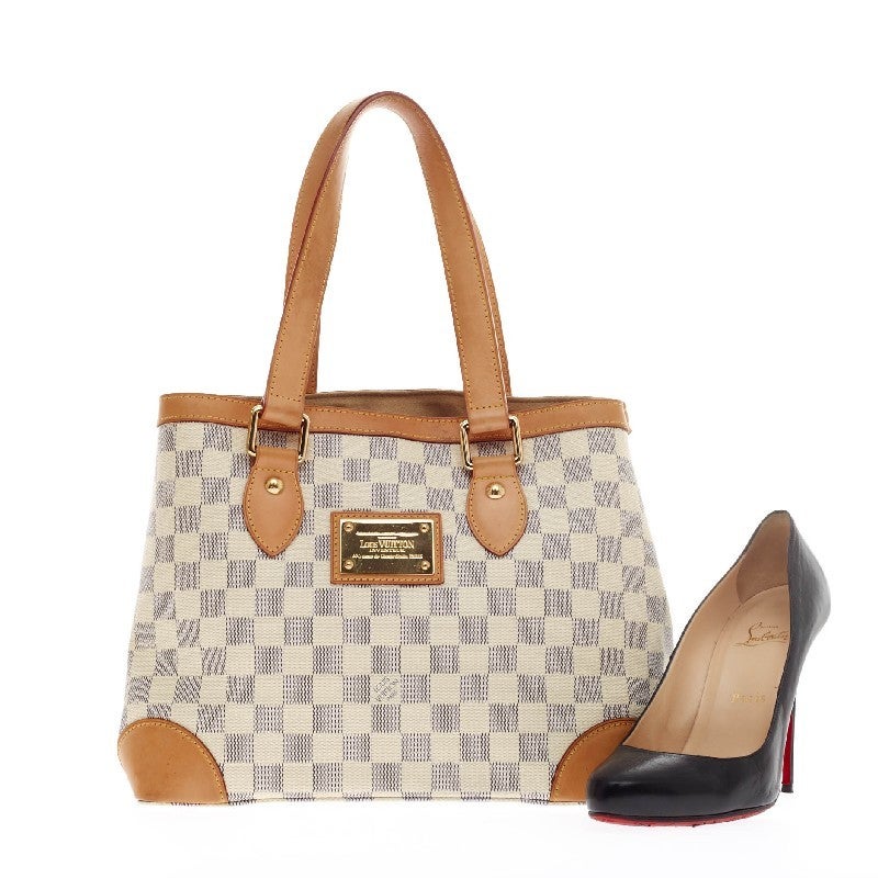 This authentic Louis Vuitton Hampstead Damier Canvas PM is a chic and durable everyday bag to suit your casual looks. Crafted from Louis Vuitton's signature damier azure print canvas, this practical tote is designed with cowhide leather trimming and