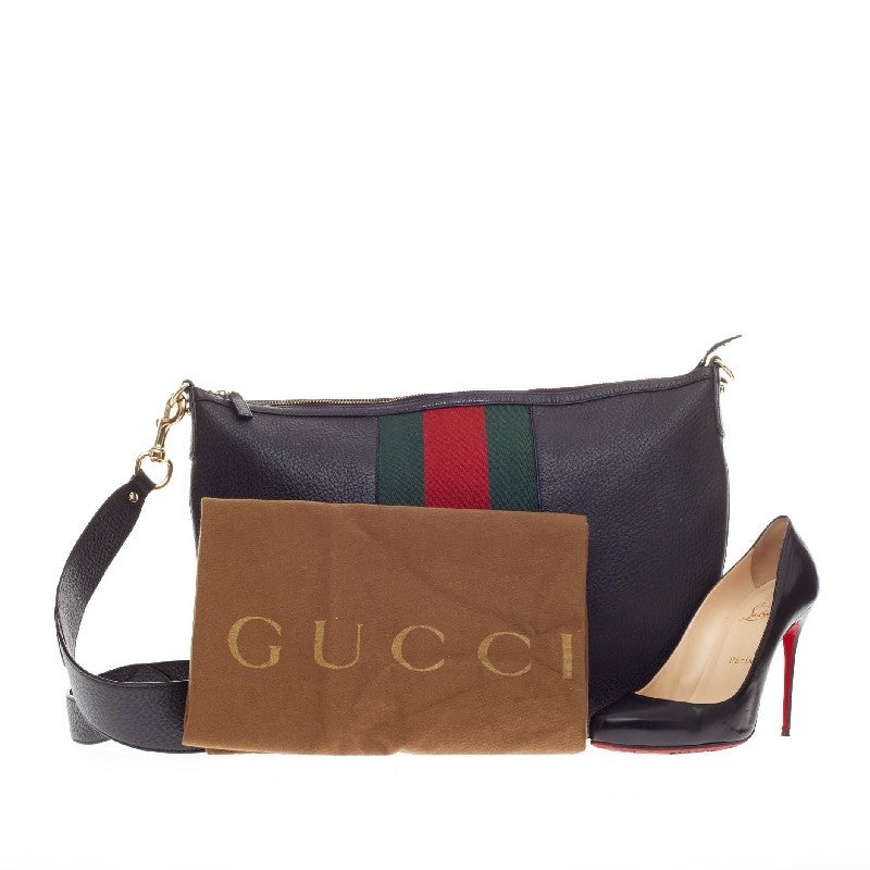 This authentic Gucci Blondie Hobo Leather with Stripes is perfect for on-the-go fashionistas. Crafted in black pebbled leather with signature Gucci web green and red stripes, this no-fuss hobo features a large gold interlocking Gucci GG logo at its