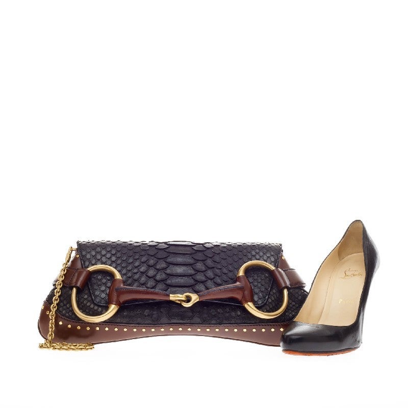 This authentic Gucci Horsebit Chain Strap Clutch Python Large is luxuriously elegant with an edgy twist perfect for a day or a night out. Crafted from genuine black python skin with wine red leather trimmings, this chic clutch features a large