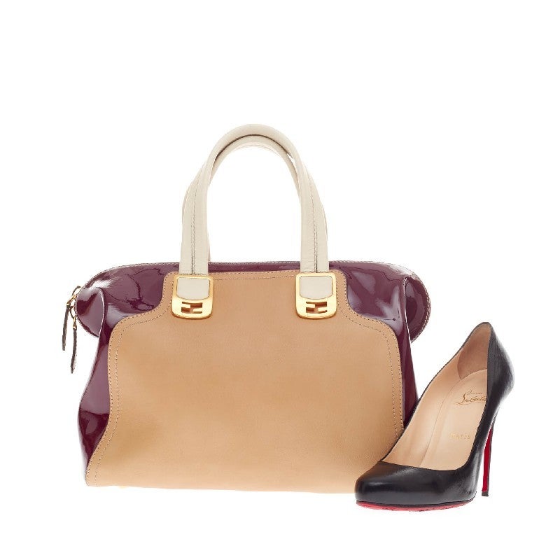 This authentic Fendi Chameleon Satchel Leather Medium showcases a simple, classic design with a modern twist. Constructed in color-blocked patent burgundy and caramel and cream leather, this stylish satchel features dual top handles accented with