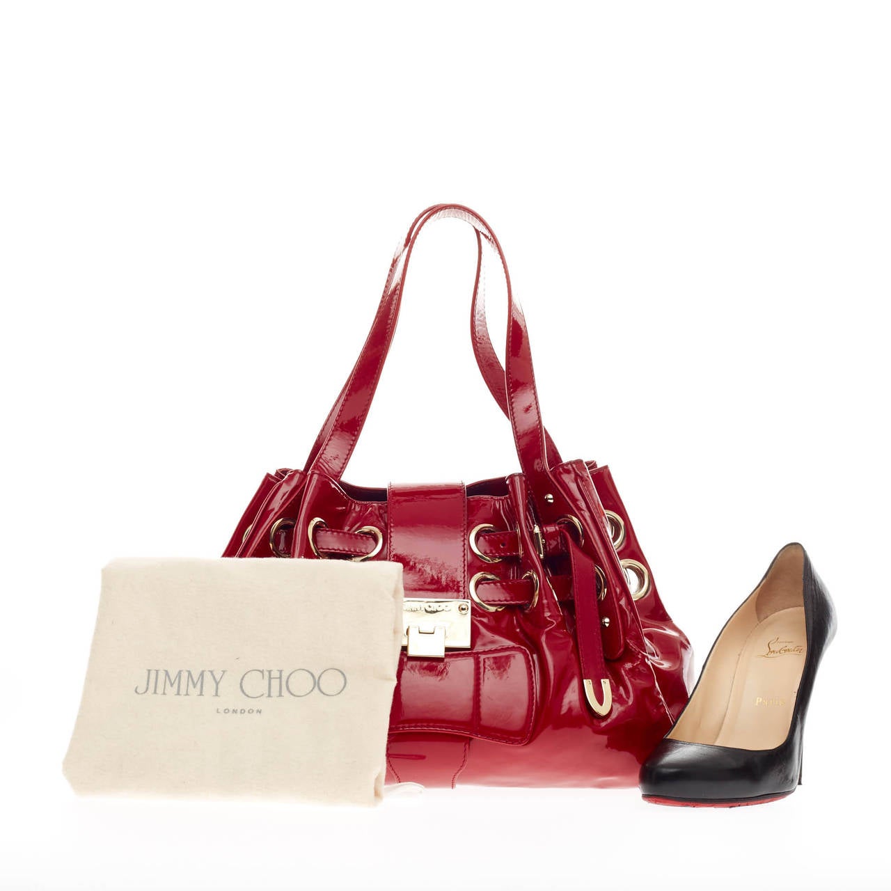 This authentic Jimmy Choo Riki Hobo Patent Medium is constructed with shiny bold red patent leather and accented with gold tone hardware. This eye-catching shoulder bag features adjustable straps woven through oversized grommet rings allowing the