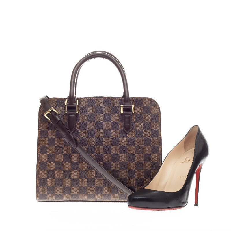 This authentic Louis Vuitton Triana Bag Damier in classic damier ebene design is perfect with any casual outfit. The bag features dark brown leather rolled handles accented with gold hardware. The gold-tone zip around closure opens to a red