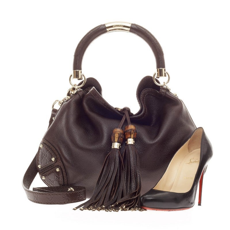 This authentic Gucci Indy Hobo Leather Medium showcases the brand's classic design with luxurious detailing adding an industrial chic twist. Crafted from supple dark brown leather, this eye-catching hobo features bamboo and fringe tassels, gg print