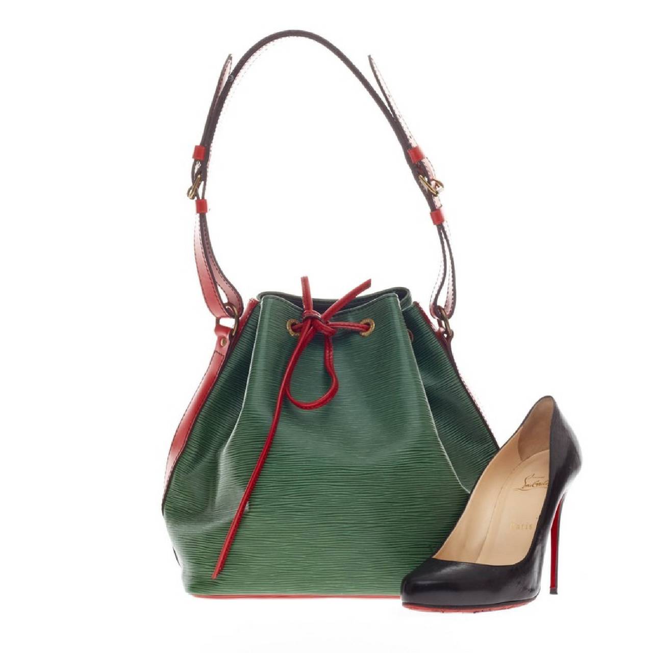 This authentic Louis Vuitton Petit Noe Two Tone Leather showcases the brand's traditional and timeless bucket design with a playful twist. Crafted in vibrant bicolor green with red epi leather accents, this eye-catching bag features an adjustable