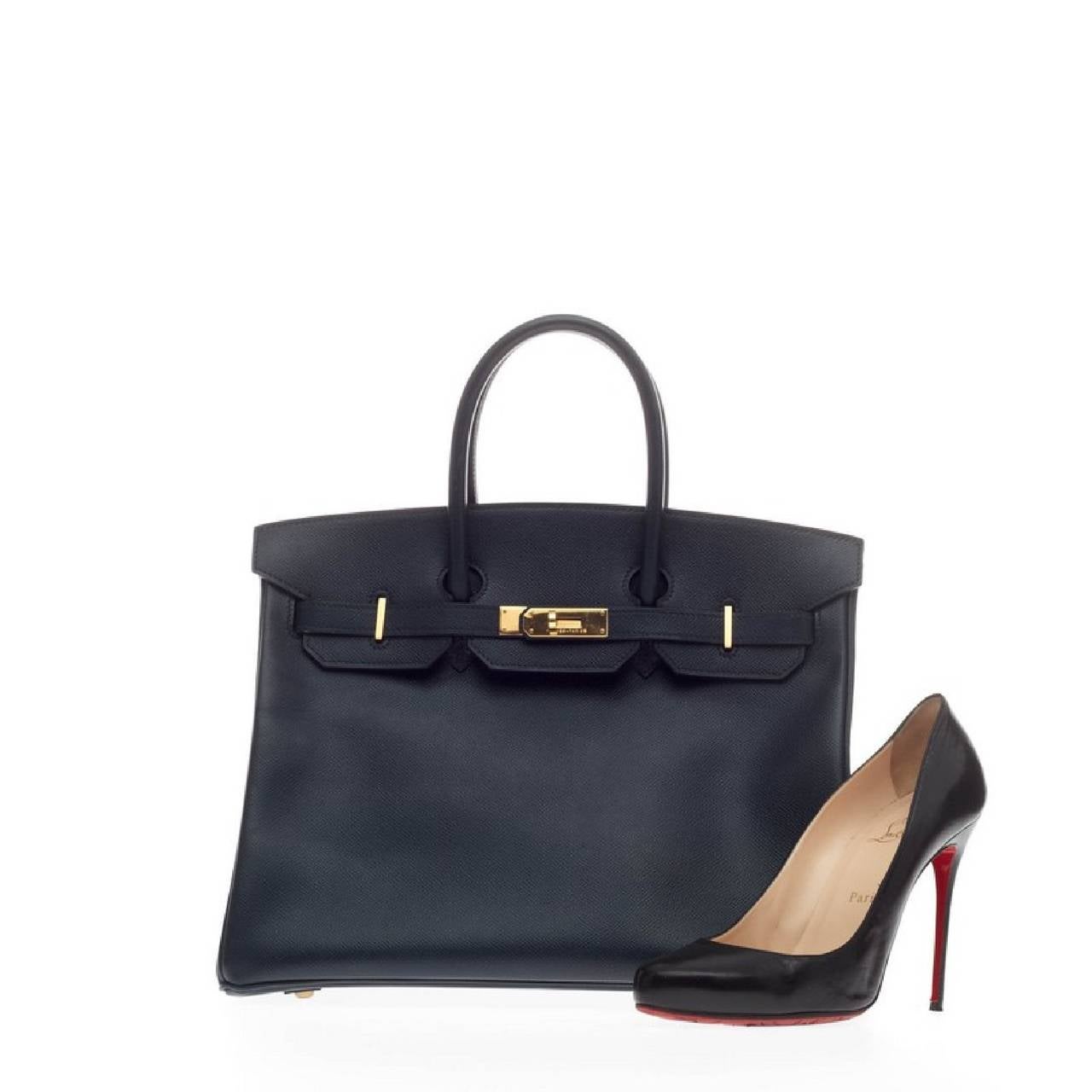 This authentic Hermes Birkin Bleu Marine Courchevel with Gold Hardware 35 is one of the most desired items of any fashionista. Finely crafted in courchevel stamped leather in stunning navy bleu marine, this coveted bag features rolled leather top
