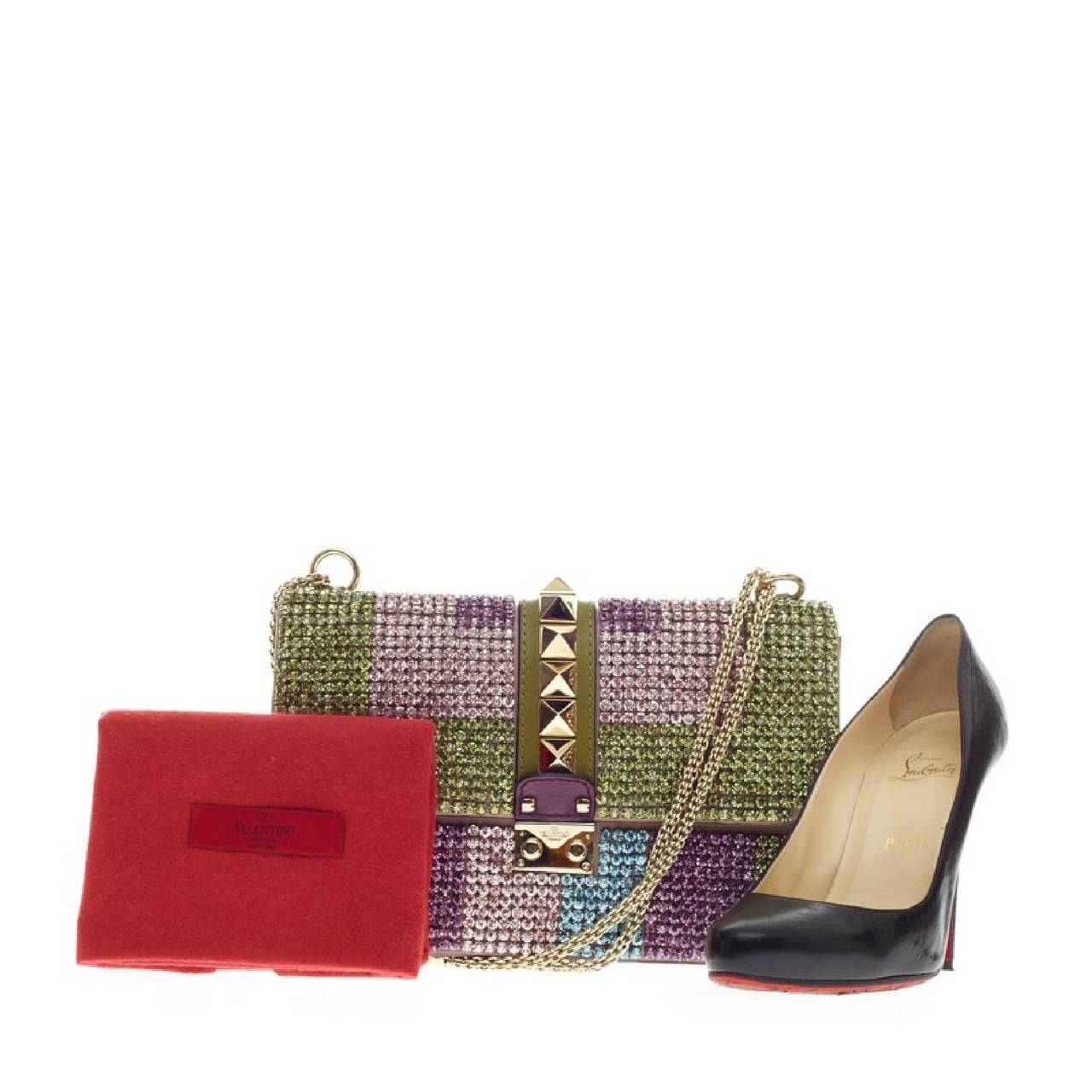 This authentic Valentino Glam Lock Shoulder Bag Rhinestones Medium is a fun, exciting and bold accessory perfect for night outs. Embellished in shimmering multicolor rhinestones of green, purple and blue striped pattern and leather, this