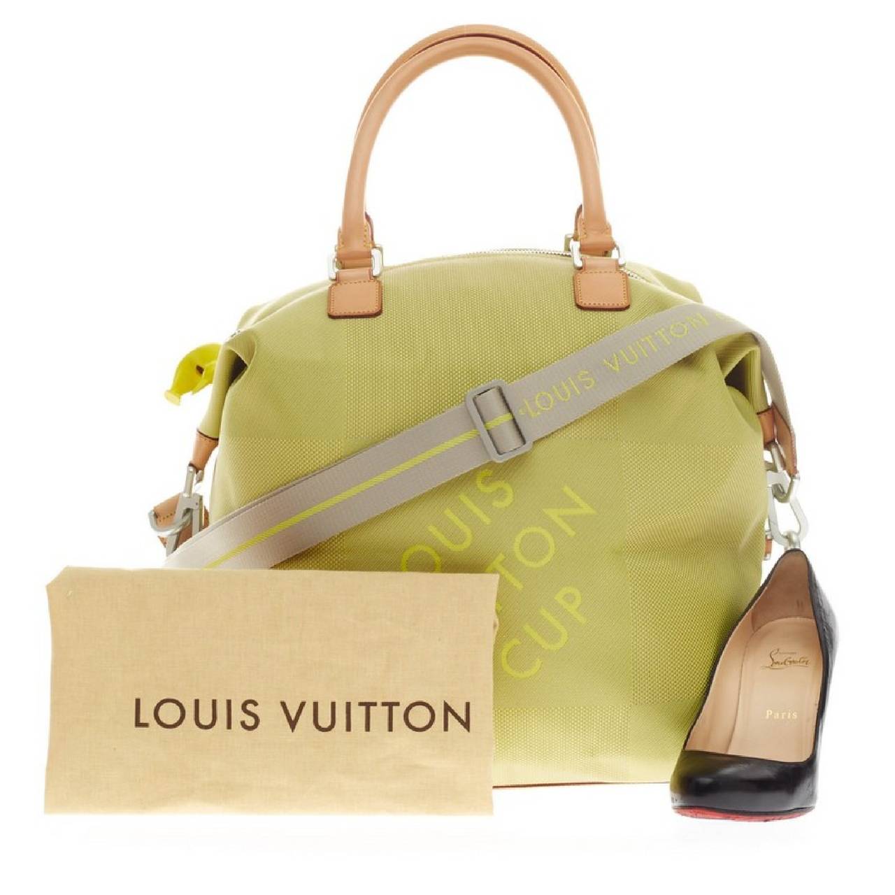 This authentic Louis Vuitton Cup Geant Cube Bag Limited Edition Canvas released only during the brand's yachting competition in 2002 is a hard-to-find piece perfect for light traveling. Crafted in eye-catching lime green and yellow damier geant