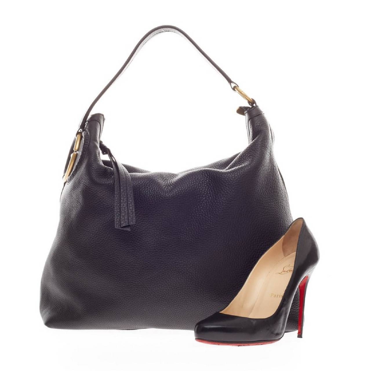 This authentic Gucci Twill Hobo Leather is perfect for everyday casual look with its lightweight and simplistic nature. Crafted in supple black twill leather, this stylish hobo features a single flat leather shoulder strap with rings, interlocking G