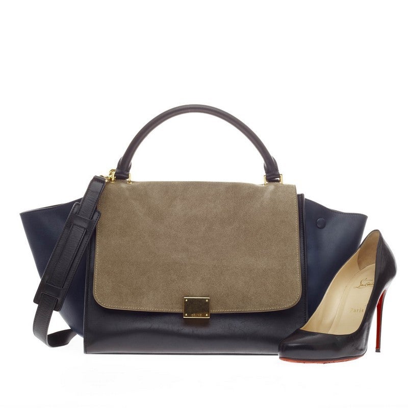 This authentic Celine Trapeze Suede Medium is a modern classic, featuring a taupe suede frontal flap, black leather body and navy leather wings. With its neutral color palette, gold-tone hardware and minimalist design, this bag will complement a