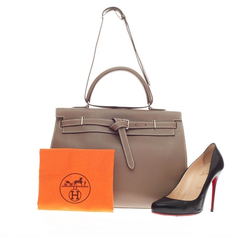 This authentic hard-to-find Hermes Kelly Flat Etoupe Swift with Palladium Hardware 35 showcases a reinterpretation of the classic Kelly design made for sophisticated traveling for any fashionista. Designed from sleek taupe swift leather and accented