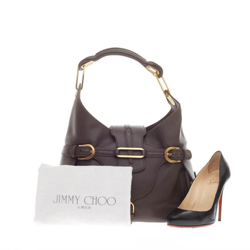 This authentic Jimmy Choo Tulita Hobo Leather Large is a stylish hobo perfect for a modern woman. Crafted from smooth chocolate brown leather, this understated bag features a single rolled top handle, buckle details, side pockets, protective base