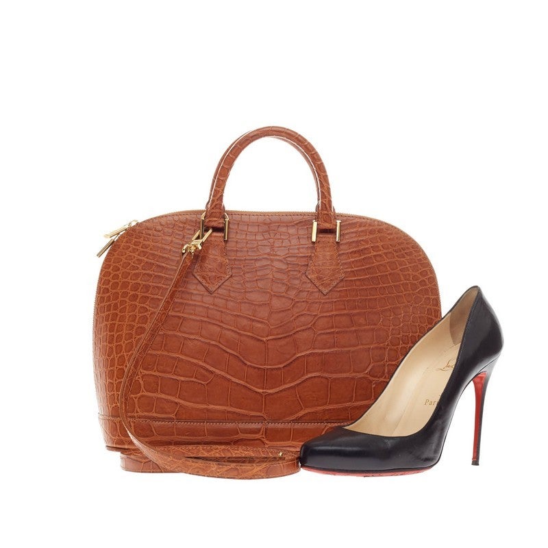 This authentic hard-to-find Louis Vuitton Alma Alligator PM mixes the brand's traditional style with luxurious flair. Constructed with genuine cognac alligator skin, this one-of-a kind bag's structured and dome-like design is ideal for casual and