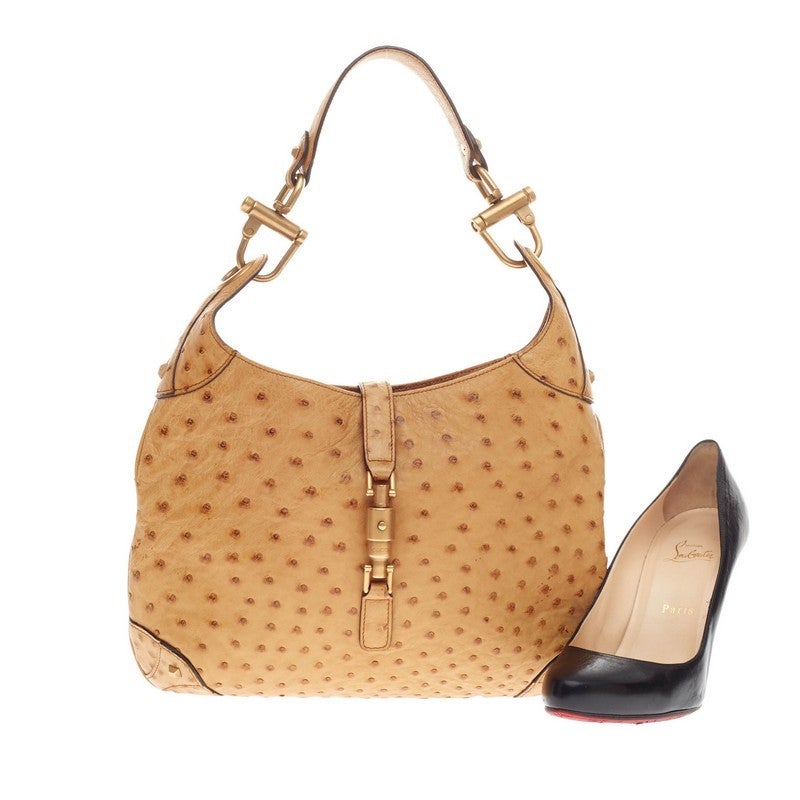 This authentic Gucci Jackie O Ostrich Medium showcases the brand's iconic Jackie bag in luxurious style perfect for everyday use. Crafted in sandy tan genuine ostrich skin, this timeless bag features a top flat handle with matte gold-tone hardware