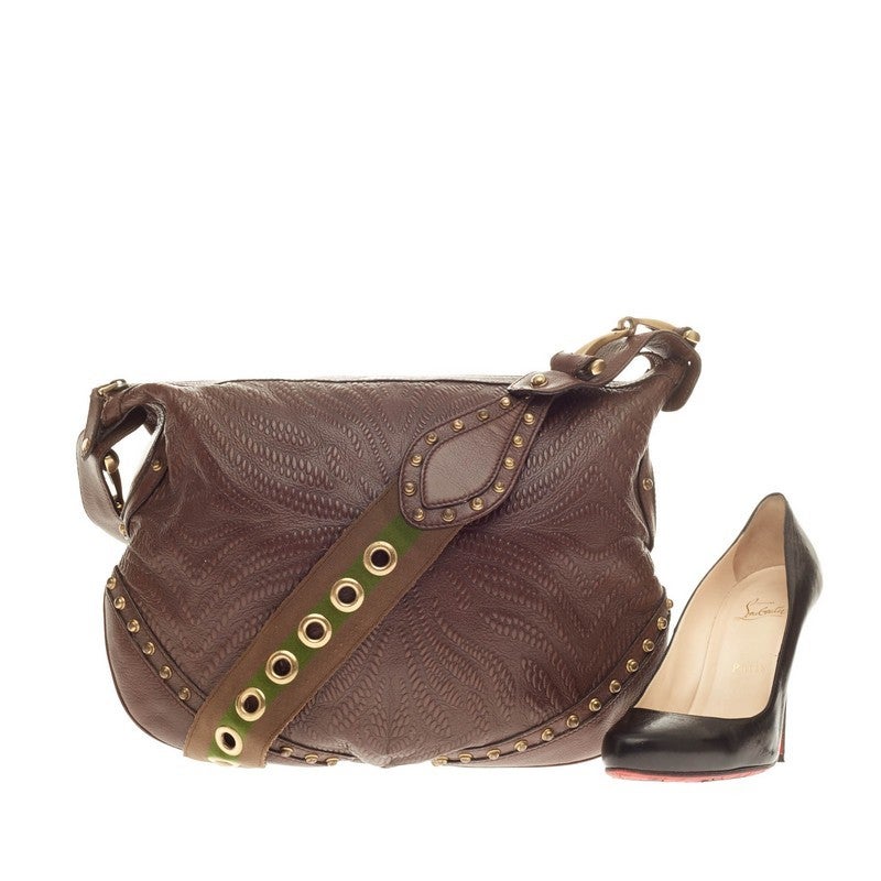 This authentic Gucci Pelham Shoulder Bag Embossed Studded Leather showcases a traditional, utilitarian design with a western-style twist. Constructed in brown embossed leather, this studded saddle bag features Gucci's trademark green and brown