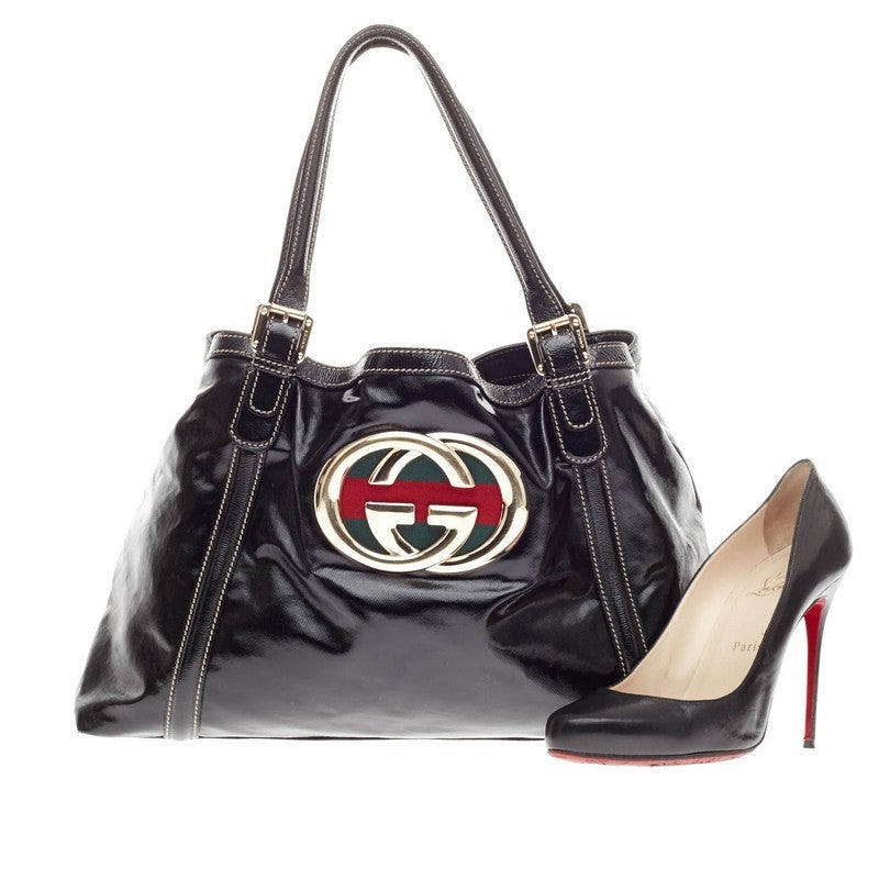 This authentic Gucci Dialux Britt Tote Patent is perfect for everyday use. Crafted in black patent leather, this bag features an oversized metal GG logo at its front with signature red and green stripes, adjustable leather shoulder strap with buckle