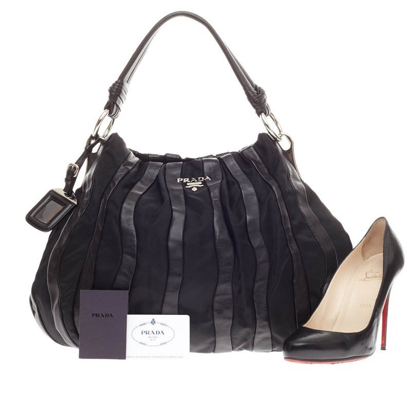 This authentic Prada Waves Shoulder Bag Leather and Tessuto Large is a stylish an functional everyday bag perfect for the modern woman. Crafted from alternating black nylon and leather stripes, this pleated bag is accented with silver-tone hardware