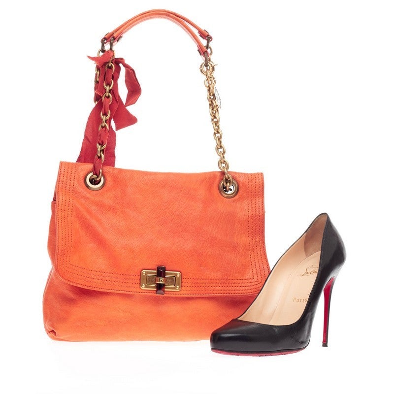 This authentic Lanvin Happy Shoulder Bag Leather Medium is the perfect companion in your daily casual look. Crafted in vivid orange leather, this feminine yet chic flap bag features a complementing signature red ribbon in brass chain straps, Lanvin