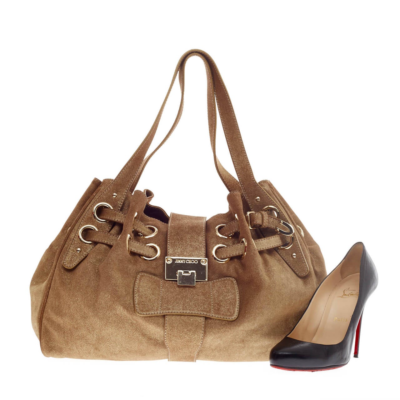 This authentic Jimmy Choo Riki Hobo Suede Medium constructed in shimmery gold suede showcases a feminine yet stylish bag perfect for the modern woman. This eye-catching shoulder bag features adjustable straps woven through oversized grommet rings