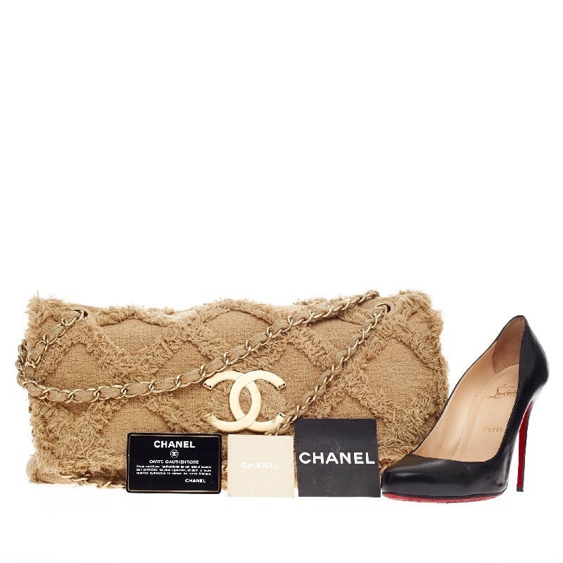 This authentic Chanel Fringe Trim Flap Bag Quilted Tweed Jumbo is a beautiful piece to hold for a night out or to add style to a daily casual outfit. Constructed in beige quilted fringed tweed and matte gold-tone brass hardware, this unique flap