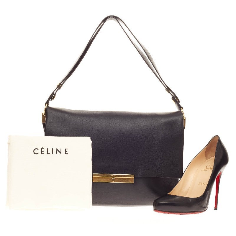 This authentic Celine Blade Shoulder Bag Leather is an elegant, minimalistic bag for any casual or sophisticated outfit. Crafted in soft black leather and accented with gold-tone hardware, this versatile bag can be worn longer on the with the button