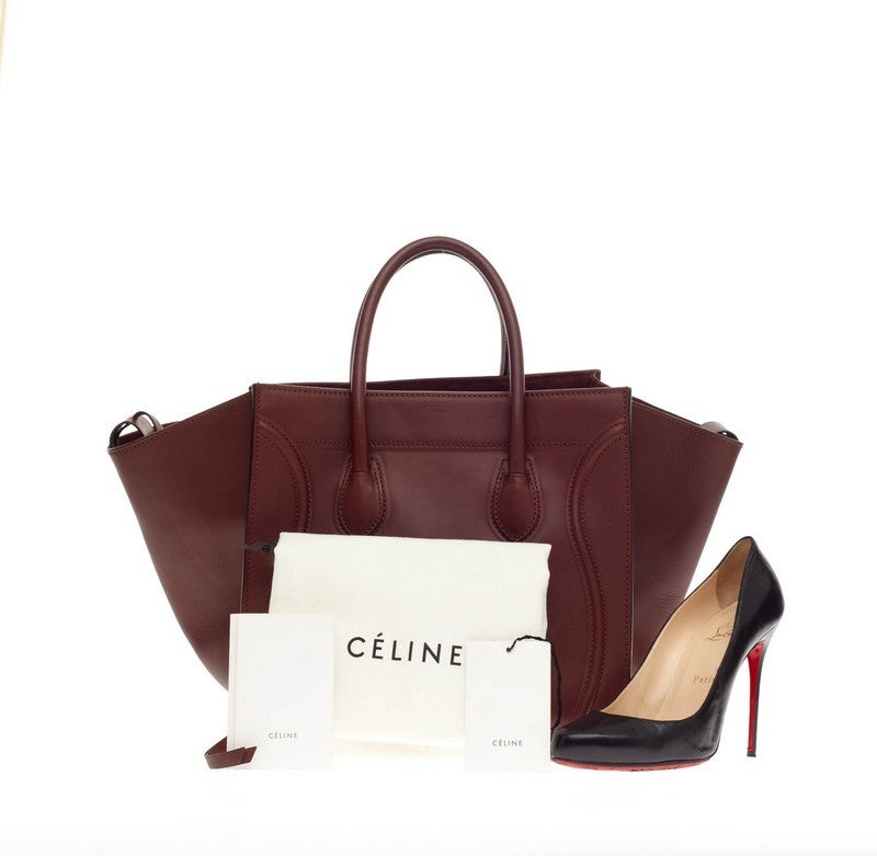 This authentic Celine Phantom Smooth Leather Medium is one of the most sought-after bags beloved by fashionistas. Crafted from rich burgundy leather, this oversized minimalist tote features a braided zipper pull, brass-tone zipped front pocket,