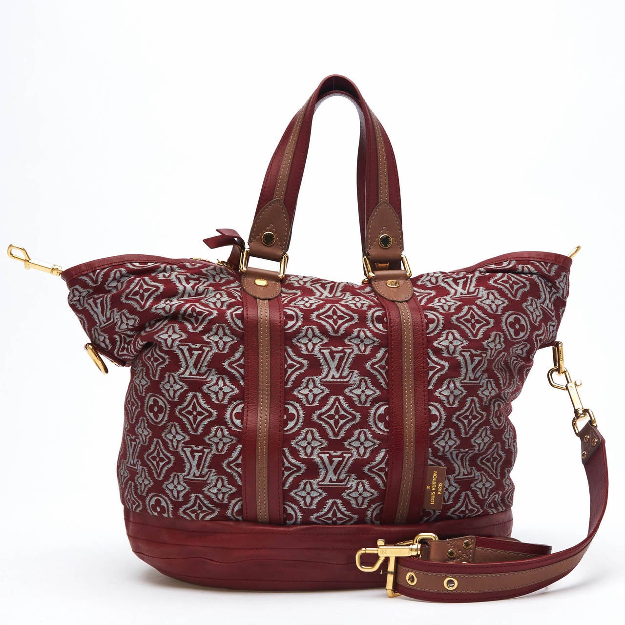 This Louis Vuitton Limited Edition Aviator Canvas is eye-catching. It features a thick monogram jacquard fabric on a slouchy silhouette, and is accented with a plum red leather base and striped handles. It is accented with gold tone hardware. It