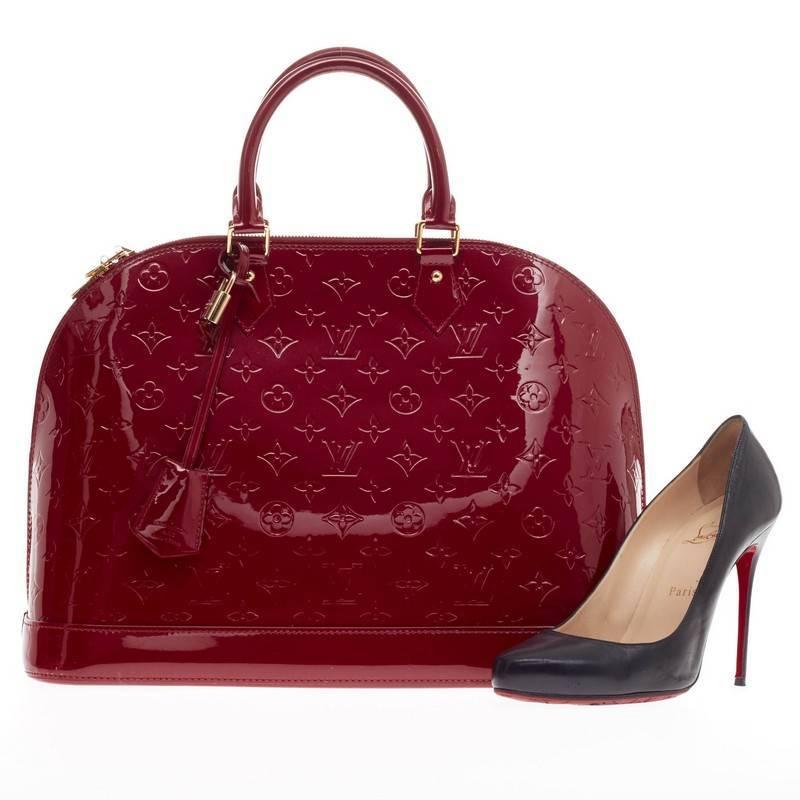 This authentic Louis Vuitton Alma Monogram Vernis GM is a fresh and elegant spin on a classic style that is perfect for all seasons. Crafted from Louis Vuitton's glossy vernis patent leather in beautiful pomme d’amour red, this dome-shaped satchel