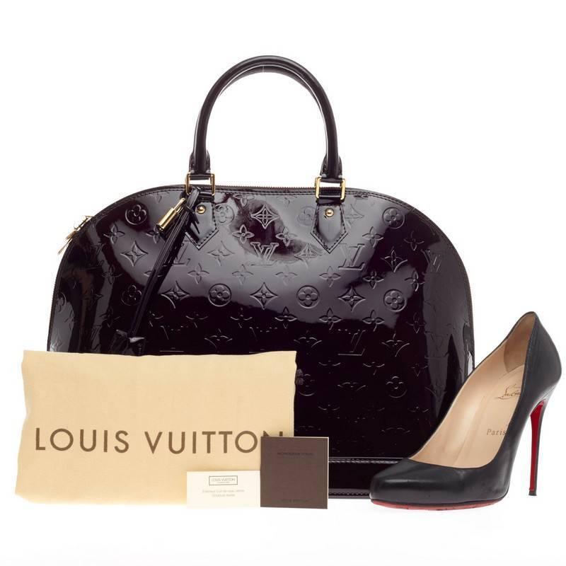 This authentic Louis Vuitton Alma Monogram Vernis GM is a fresh and elegant spin on a classic style that is perfect for all seasons. Crafted from Louis Vuitton's glossy vernis patent leather in beautiful amarante dark purple, this dome-shaped