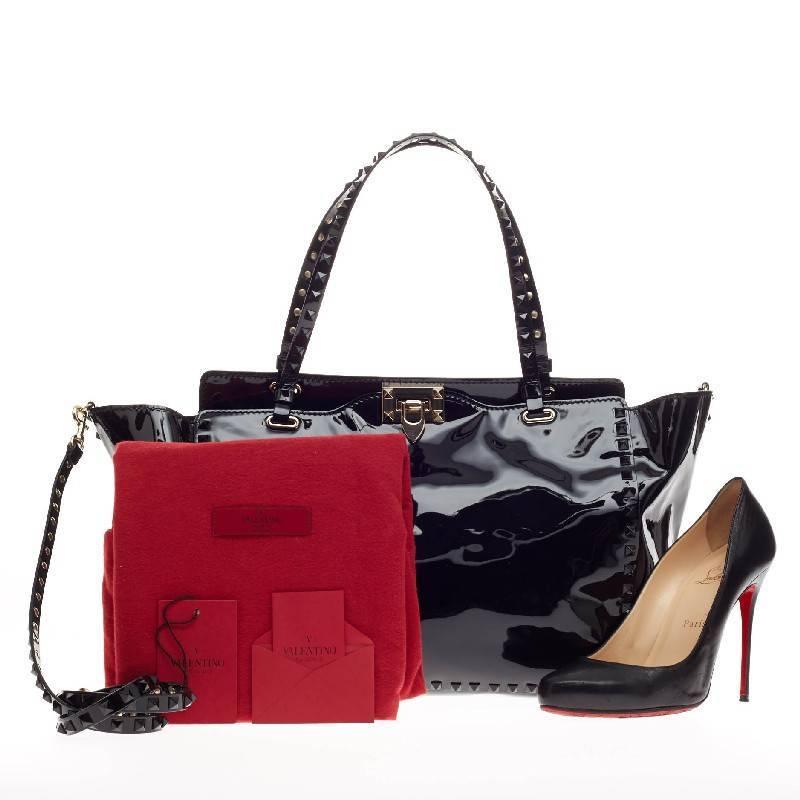 This authentic Valentino Rockstud Tote Patent Medium presents a sleek design with an edgy twist made for daring fashionistas. Crafted from bold, black patent leather, this popular tote features signature matte-black pyramid stud border and strap