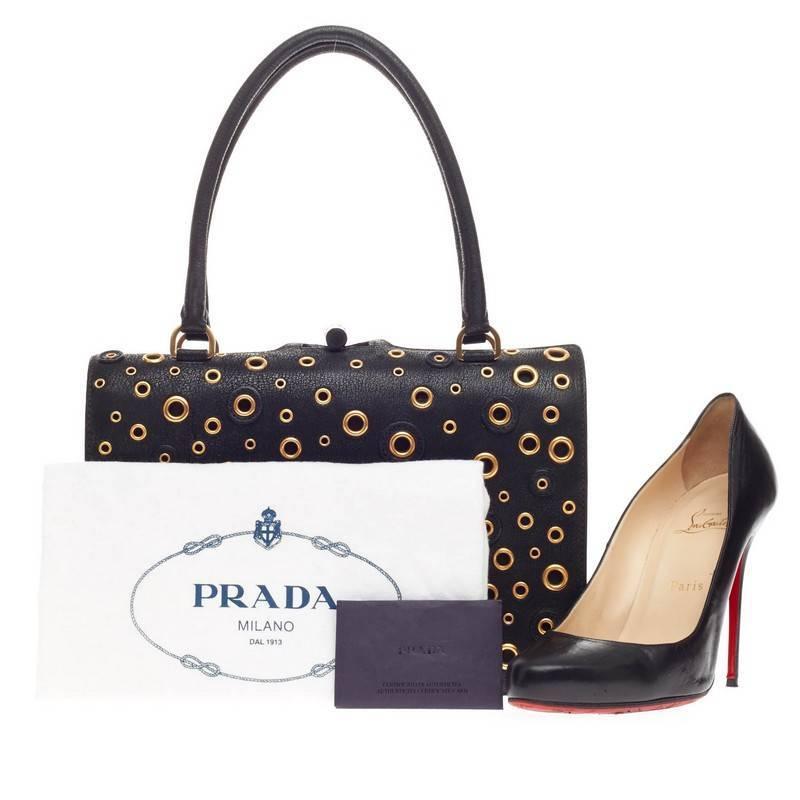 This authentic Prada Grommet Top Handle Frame Bag Leather is an eye-catching, edgy piece perfect for night outs. Crafted in black leather, this bag features stunning grommet details throughout, Prada logo at the bottom, dual-rolled leather handles