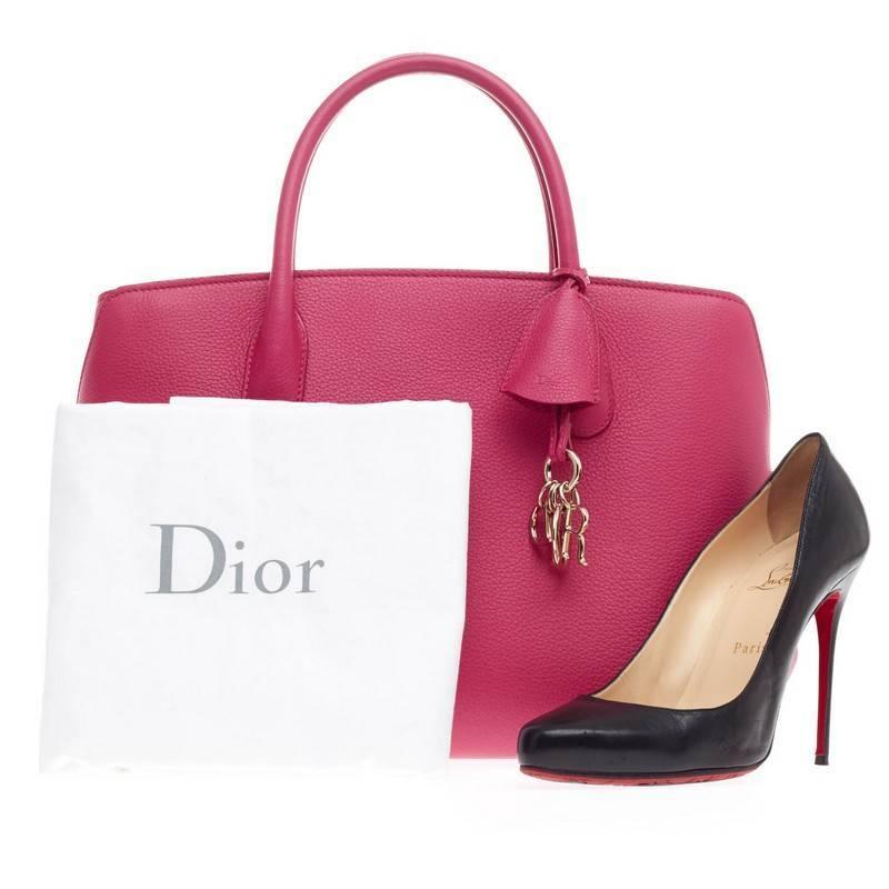 This authentic Christian Dior Bar Bag Leather Medium presented in the brand's first collection under Raf Simons takes inspiration from Dior's classic figure 8 bar jacket. Crafted in beautiful fuchsia calfskin leather, this impeccably chic tote