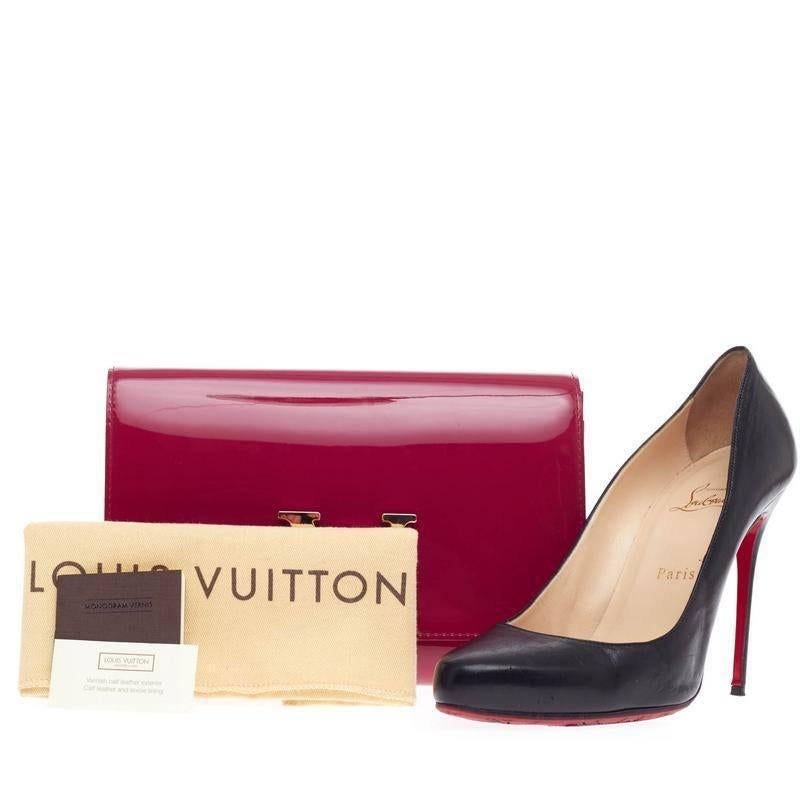 This authentic Louis Vuitton Louise Clutch Patent MM presented in the brand's 2013 Collection is perfect for night outs. Crafted in striking magenta glossy patent calfskin, this modern yet feminine clutch features an oversized LV logo flip lock