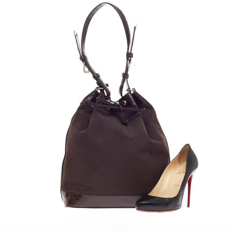 This authentic Ralph Lauren Drawstring Bucket Bag Nylon and Crocodile is perfect for stylish and on-the-go fashionista. Crafted in brown nylon with crocodile trimmings, this classic bucket bag features an adjustable strap and silver-tone hardware