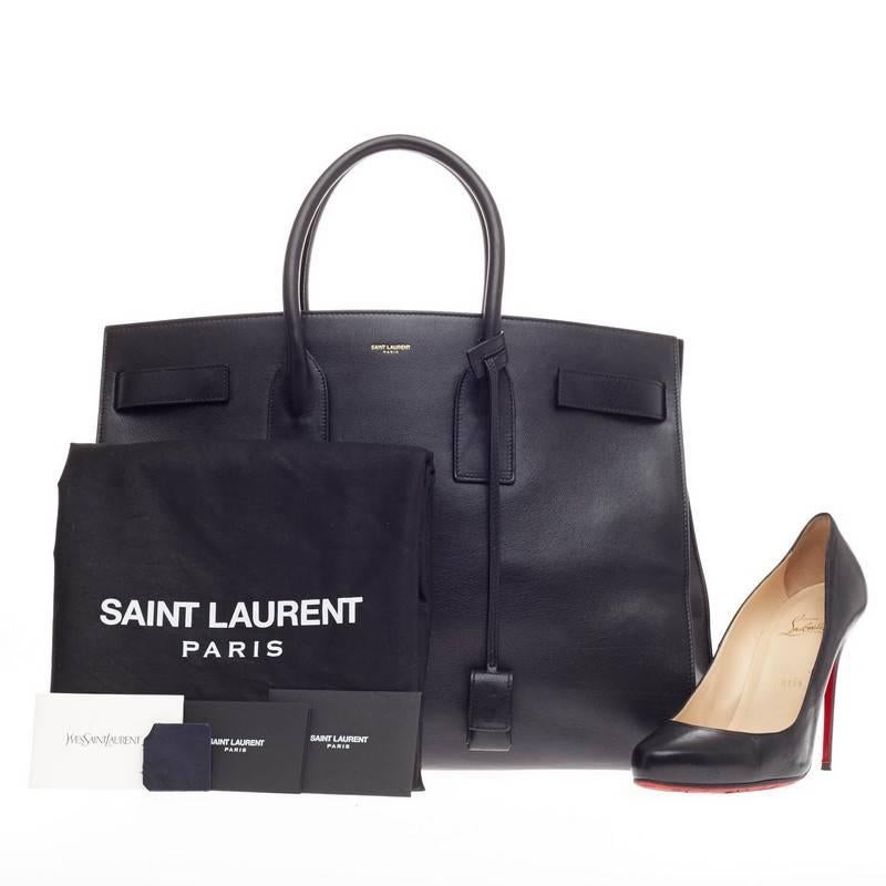 This authentic Saint Laurent Sac De Jour Leather Large is a sleek yet elegant bag synonymous with the brand's classic aesthetic. Crafted from black calfskin leather, this oversized sought-out tote features a gold Saint Laurent embossed signature at