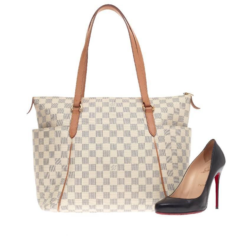 This authentic Louis Vuitton Totally Damier MM is a chic and practical bag for everyday occasions. Crafted from Louis Vuitton's iconic damier azure print, this simple city tote features tall cowhide leather handles and trims, two exterior lateral