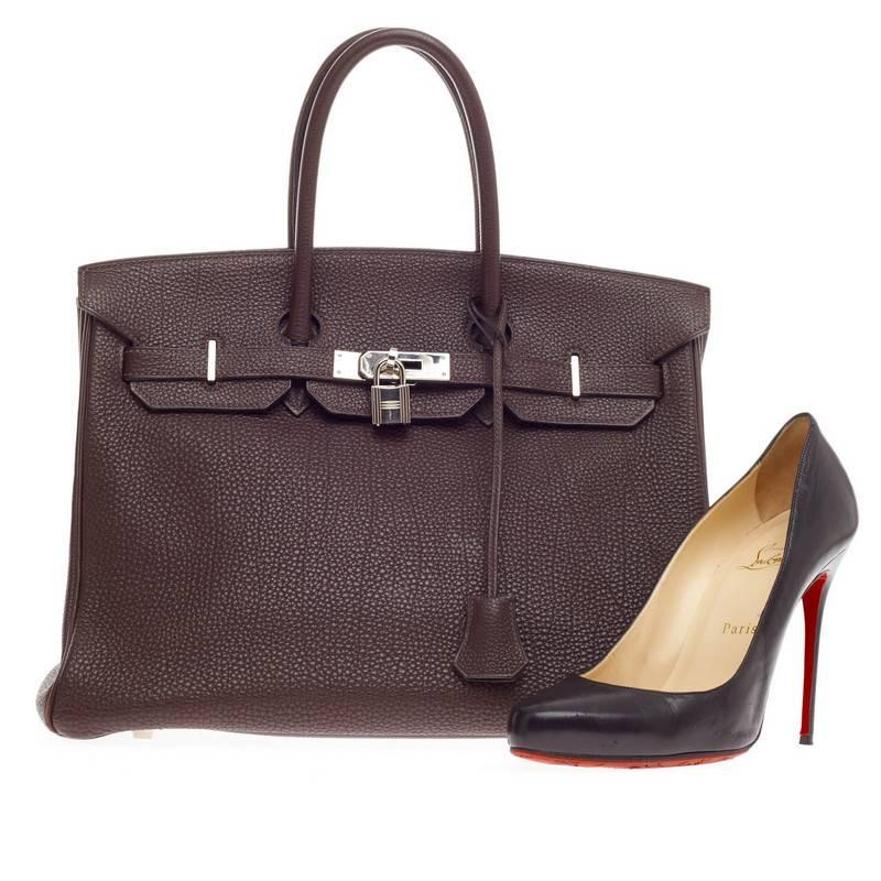 This authentic Hermes Birkin Ebene Togo with Palladium Hardware 35 is the quintessential dream bag for the modern woman. Crafted in luxurious and scratch-resistant dark brown ebene togo leather, this iconic tote features dual-rolled top handles,