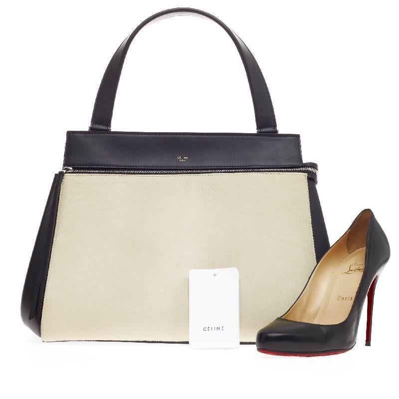 This authentic Celine Edge Bag Pony Hair Medium is striking in its simplicity and structure. Constructed in black leather and ivory pony hair, this boxy bag showcases zip-around detail, side snap closures, single looped shoulder strap, exterior back