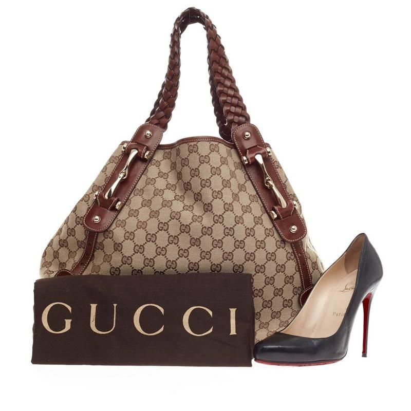 This authentic Gucci Pelham Shoulder Bag GG Canvas Medium is ideal for everyday use. Constructed with Gucci's monogram canvas with brown leather trimmings, this bag features braided leather handles, gold studs details, signature gold horsebit