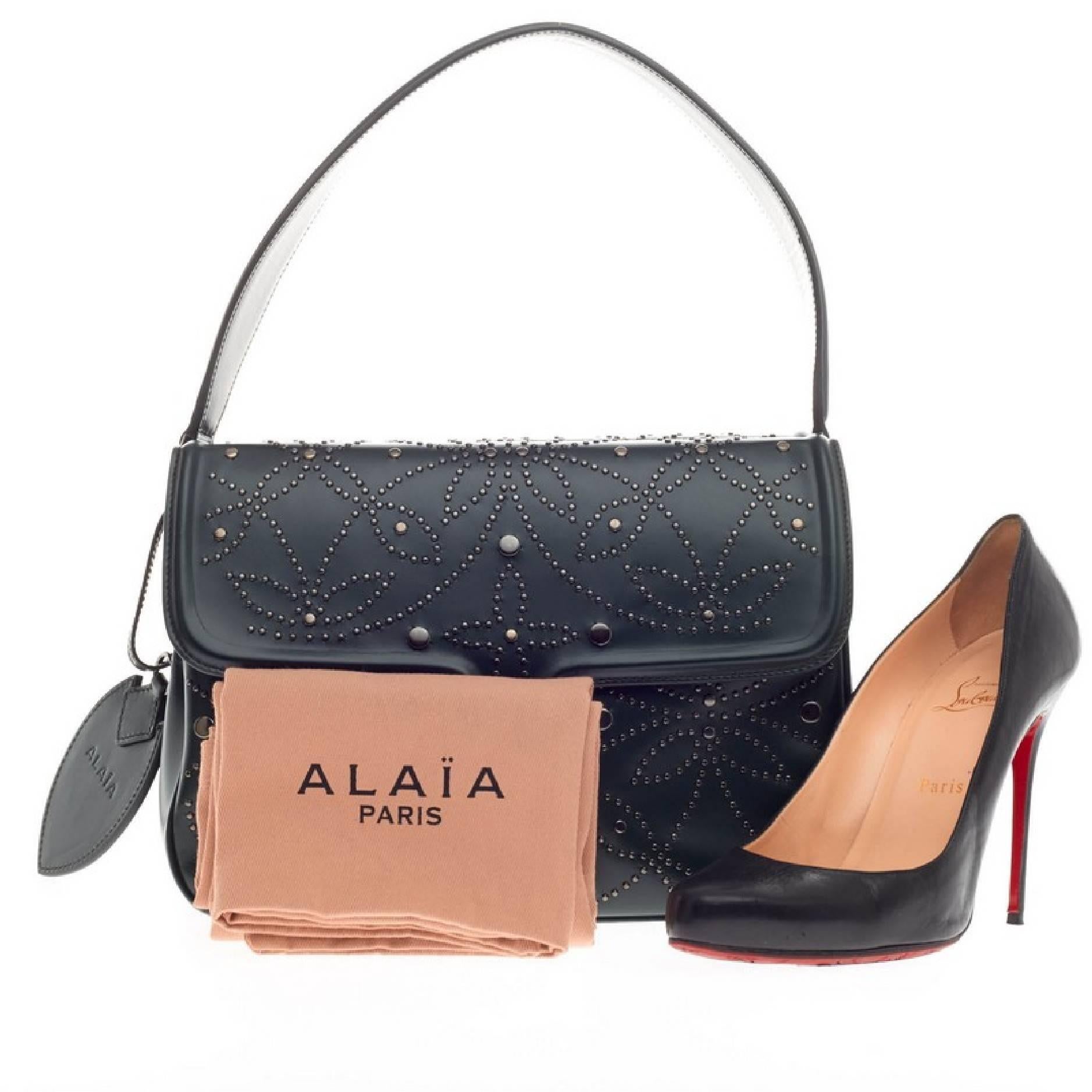 This authentic Alaia Symmetrical Flap Bag Studded Leather personifies the brand's quintessential sleek yet chic everyday style. Constructed in smooth dark green leather with a beautiful floral silver studded design, this double-sided, symmetrical