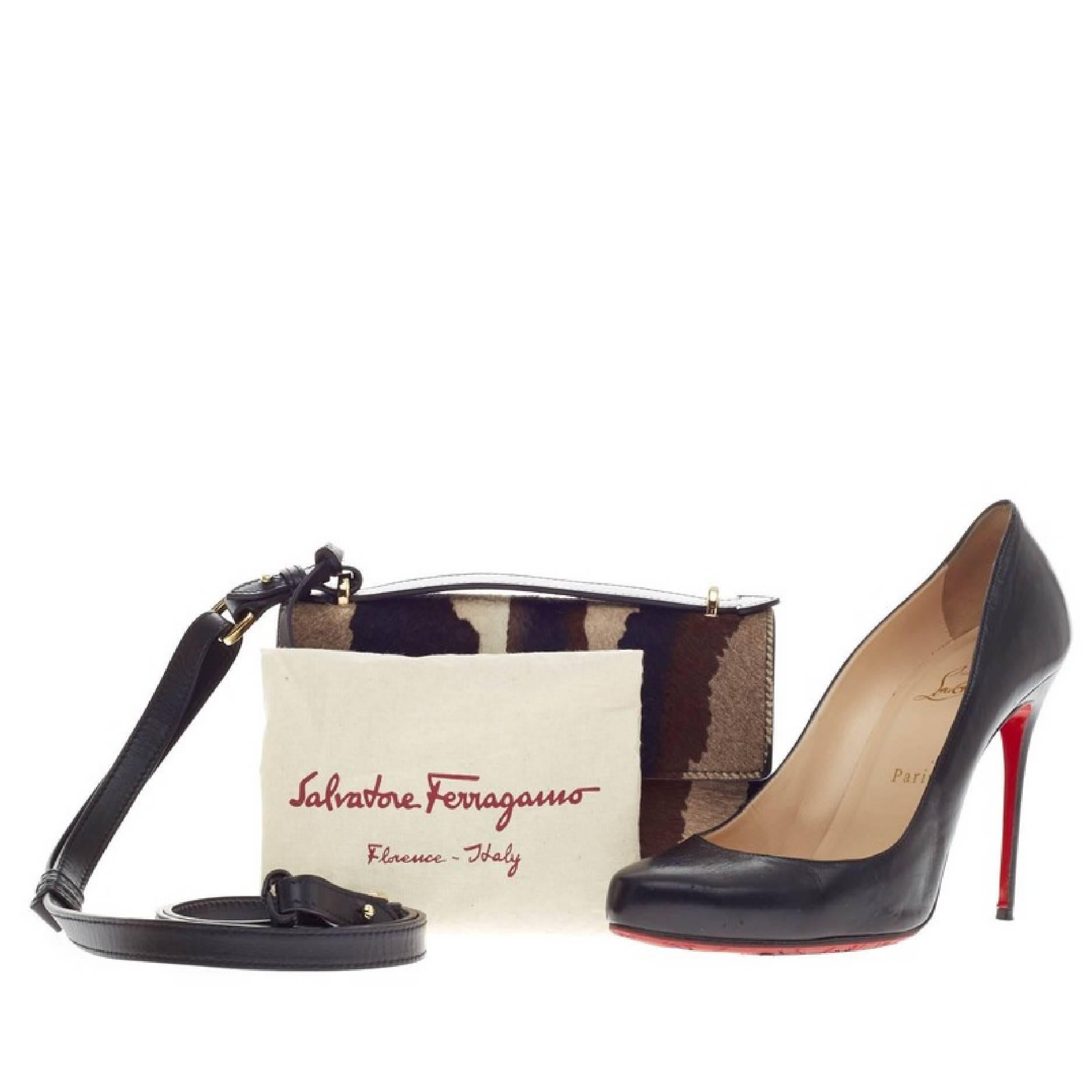 This authentic Salvatore Ferragamo Gancio Lock Shoulder Bag Pony Hair Mini is an eye-catching piece among fashionistas. Crafted in pony hair in shades of brown, black and white, this miniature, structured bag features a frontal flap with signature