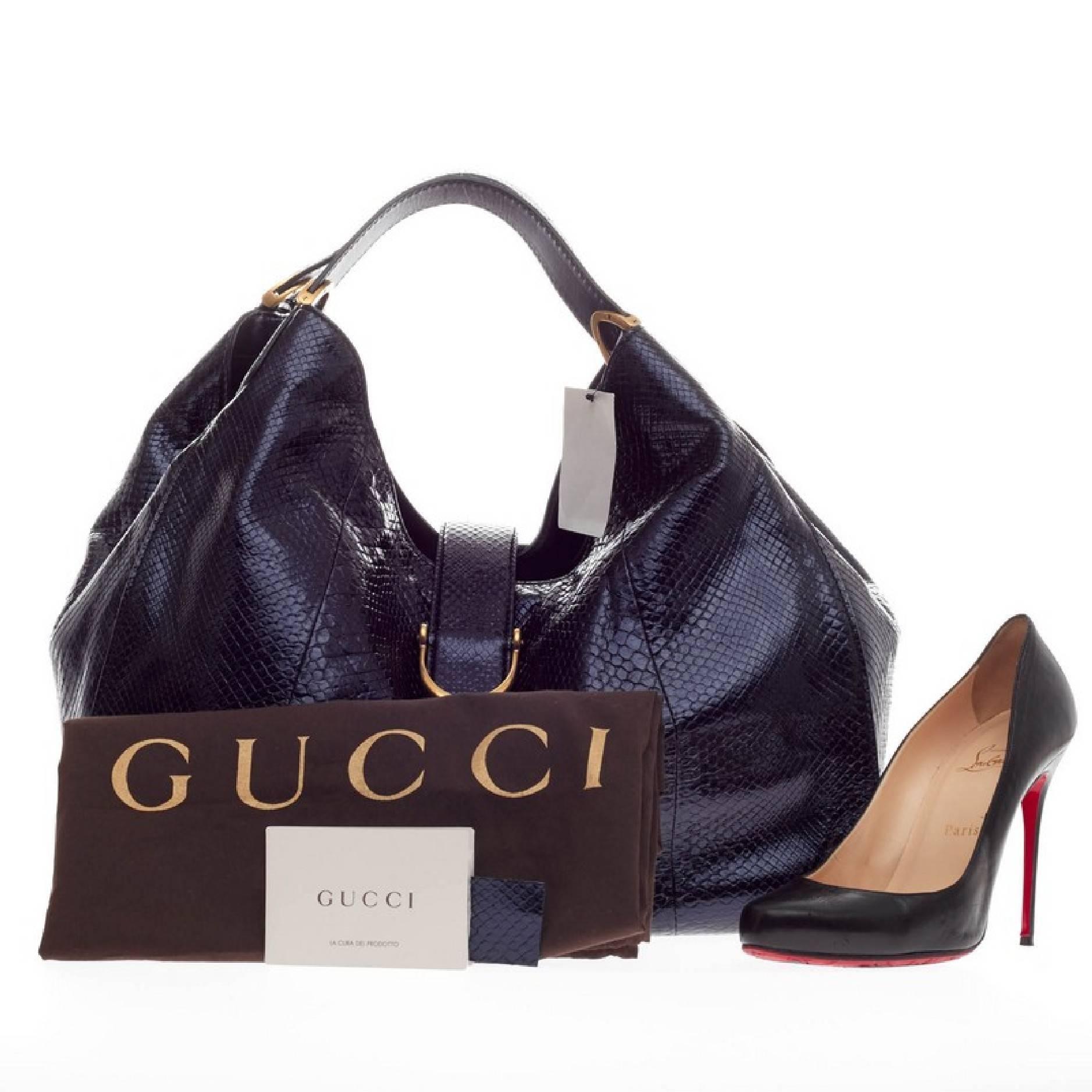 This authentic Gucci Soft Stirrup Tote Python Large in luxurious and sleek design is made for all seasons. Crafted in metallic navy blue genuine python skin, this exotic hobo-style shoulder bag features side to side looped dual-flat handles with
