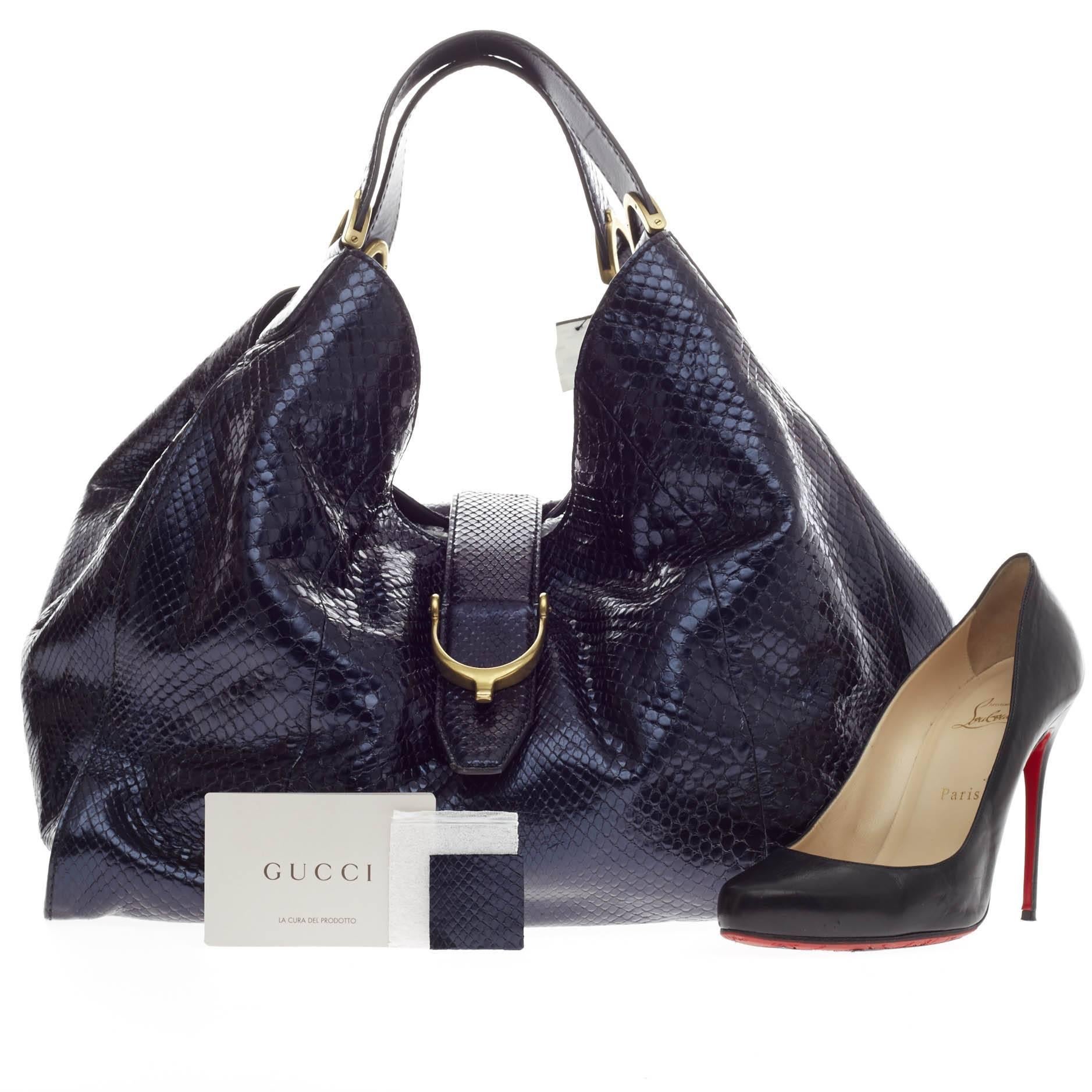 This authentic Gucci Soft Stirrup Tote Python Large in minimalist design is ideal for all season. Crafted in midnight blue python skin, this chic hobo-style shoulder bag features side to side looped dual-flat handles with unique spur detailing and
