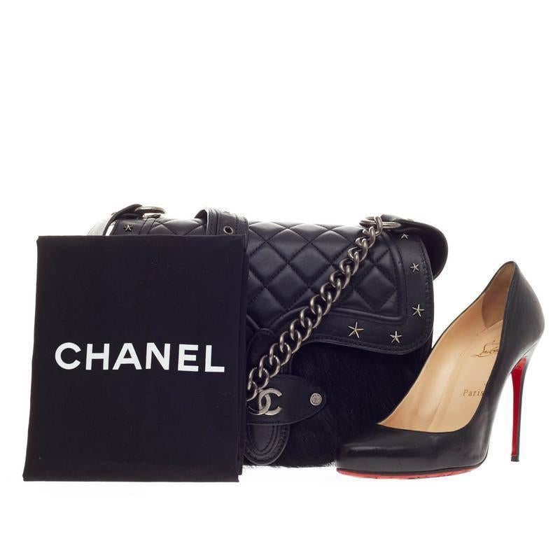 This authentic limited edition Chanel Dallas Studded Saddle Bag Quilted Calfskin and Pony Hair showcased in Chanel's Metiers d'Art 2014 collection mixes the brand's avant-garde style with a flair of Texas inspiration. Crafted from quilted black