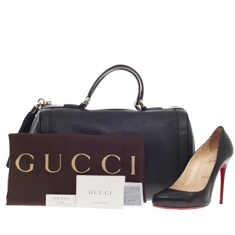 This authentic Gucci Soho Boston Leather is classic and minimalist in design ideal for everyday work or casual look. Crafted in black pebbled leather, this bag features dual-rolled handles, pull zip tassel accent, stitched oversized GG logo at the