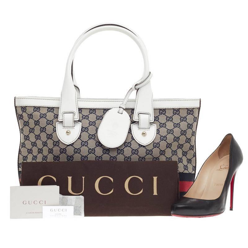 This authentic Gucci Web Heritage Tote GG Canvas Medium is classic and simple in design perfect for everyday use. Crafted in GG canvas, this tote features white leather trims and handles, black and red web stripes, belt and buckle details, leather