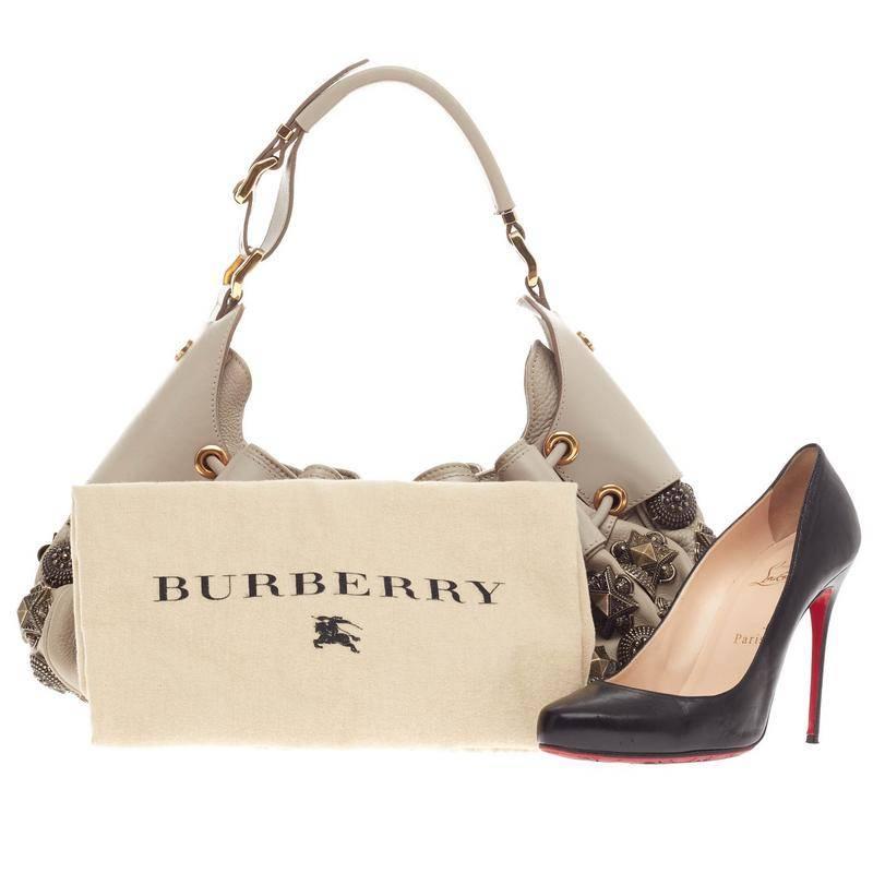 This authentic Burberry Mason Warrior Hobo Studded Leather Medium presented in the brand's Spring 2008 Collection is inspired by today's modern-day warrior. Crafted in soft taupe leather with antique-style aged gold metal stud embellishments, this